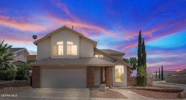 traditional home with brick siding, an attached garage, roof with shingles, and concrete driveway