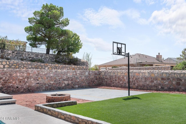 view of basketball court featuring a yard, fence, and basketball court