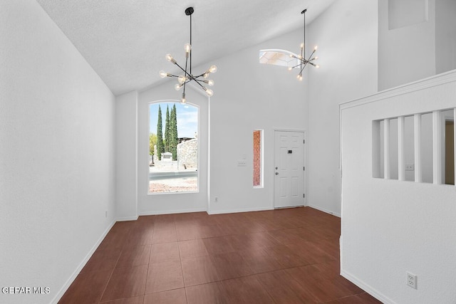 foyer with baseboards, a chandelier, and high vaulted ceiling