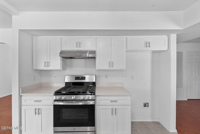 kitchen with baseboards, stainless steel gas range, light countertops, under cabinet range hood, and white cabinets