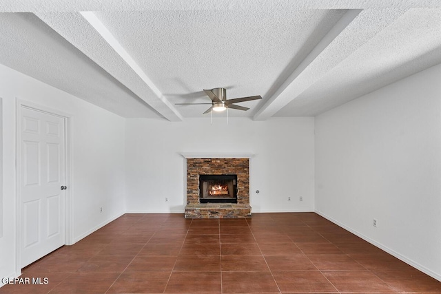 unfurnished living room featuring tile patterned flooring, beamed ceiling, a lit fireplace, a textured ceiling, and a ceiling fan