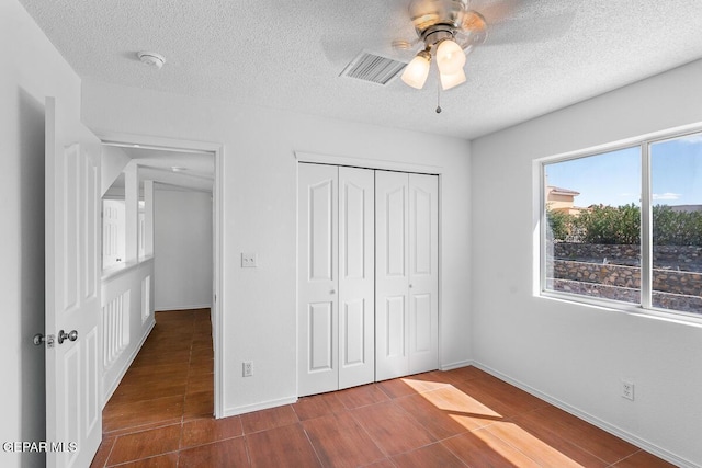 unfurnished bedroom with wood finished floors, a closet, a textured ceiling, and visible vents