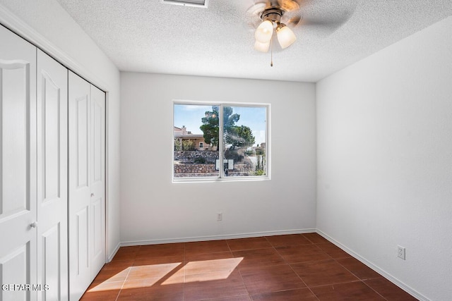 unfurnished bedroom with baseboards, a textured ceiling, ceiling fan, and a closet