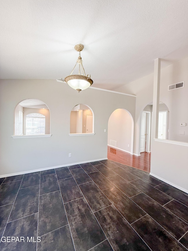 spare room with visible vents, arched walkways, and a textured ceiling