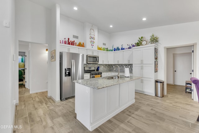 kitchen with visible vents, appliances with stainless steel finishes, a sink, a high ceiling, and white cabinetry