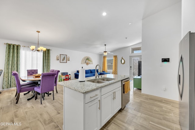 kitchen featuring pendant lighting, a sink, white cabinets, open floor plan, and stainless steel appliances