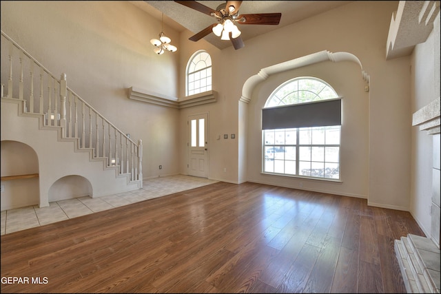 entryway featuring high vaulted ceiling, hardwood / wood-style floors, baseboards, ceiling fan, and stairs