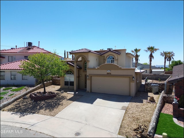 mediterranean / spanish-style house with concrete driveway, stucco siding, fence, and an attached garage