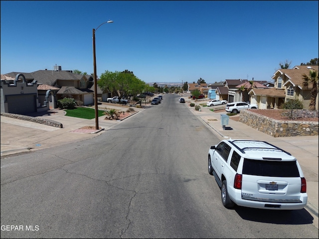 view of road featuring street lighting, a residential view, curbs, and sidewalks