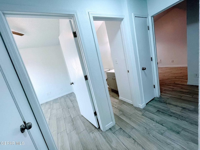 hall with baseboards and light wood finished floors