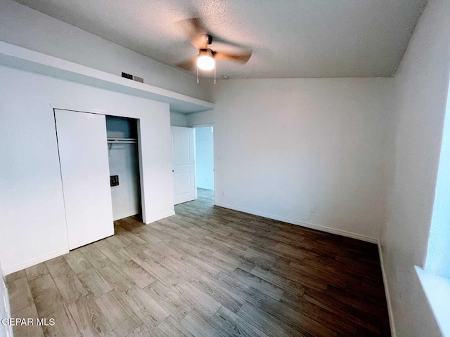 unfurnished bedroom with a closet, wood finished floors, baseboards, ceiling fan, and a textured ceiling