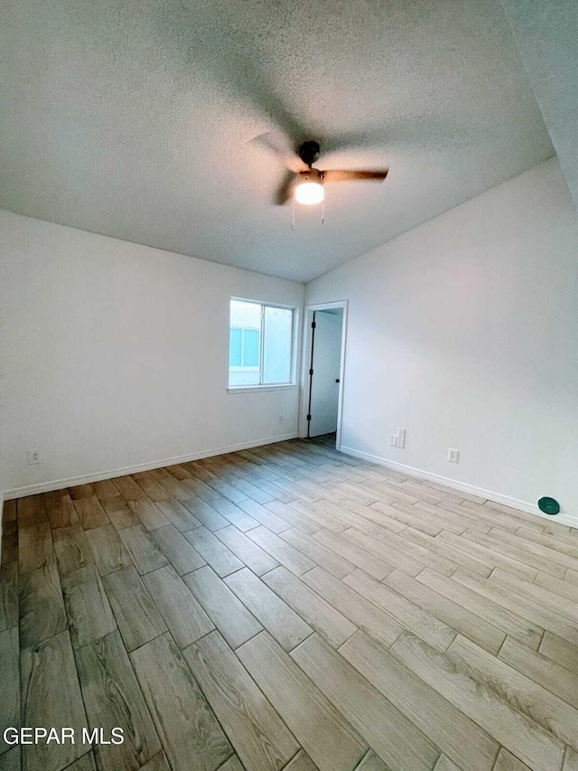 empty room with a textured ceiling, ceiling fan, baseboards, and wood finished floors