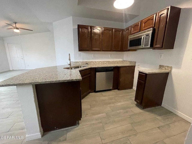 kitchen with light stone countertops, a sink, stainless steel appliances, a ceiling fan, and a peninsula