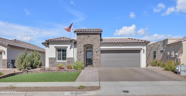 mediterranean / spanish house featuring a tile roof, stone siding, a garage, stucco siding, and concrete driveway