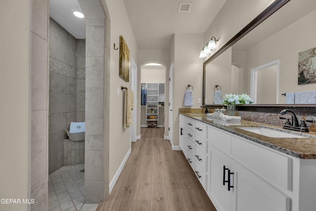 full bathroom with walk in shower, a sink, double vanity, wood finished floors, and visible vents