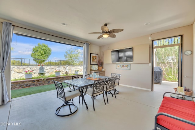 dining area featuring finished concrete flooring, baseboards, a ceiling fan, and a wealth of natural light