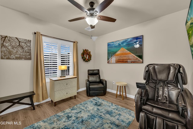 living area with a ceiling fan, baseboards, visible vents, and wood finished floors