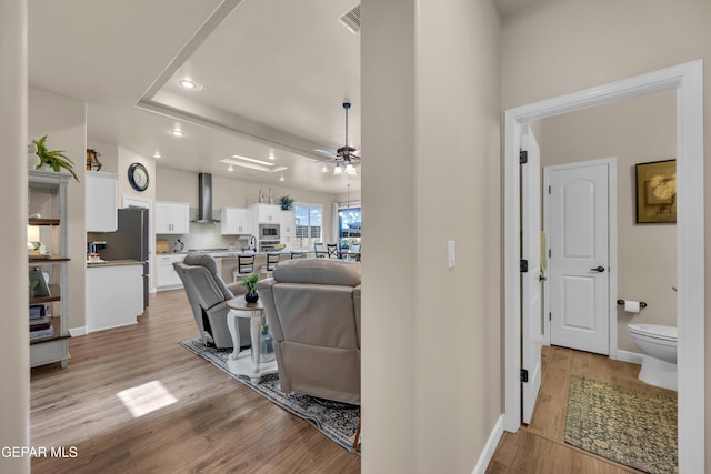 living area with a ceiling fan, visible vents, baseboards, light wood finished floors, and recessed lighting