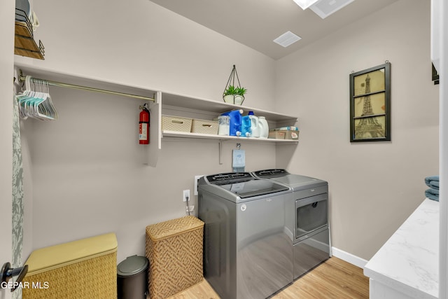laundry room with baseboards, laundry area, light wood finished floors, and washer and dryer