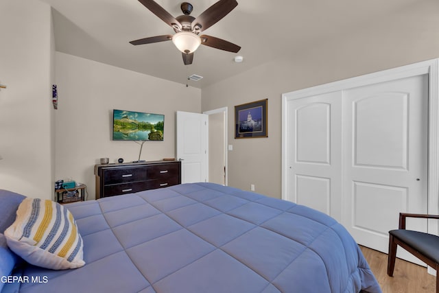 bedroom with ceiling fan, a closet, wood finished floors, and visible vents