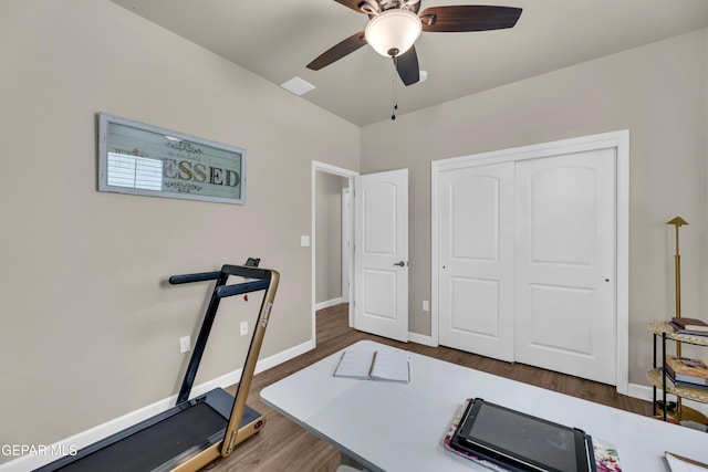workout area with baseboards, ceiling fan, and wood finished floors