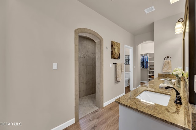 full bath featuring walk in shower, vanity, toilet, baseboards, and wood finished floors