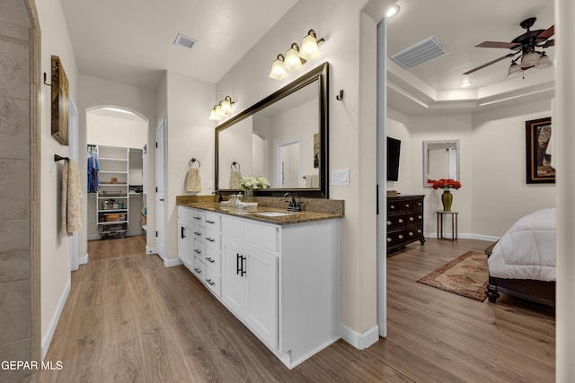 ensuite bathroom featuring a sink, wood finished floors, and visible vents