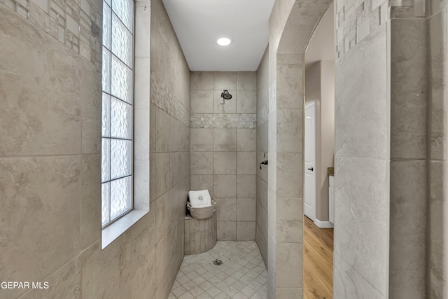 bathroom with tiled shower and wood finished floors