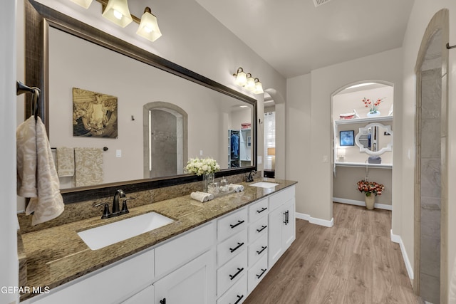 bathroom featuring double vanity, baseboards, a sink, and wood finished floors