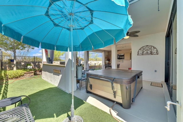 view of patio / terrace with fence, outdoor dry bar, a ceiling fan, and a hot tub