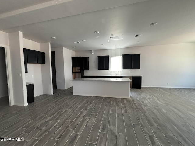 321 Merced Ct, El Paso, TX 79932 - kitchen with wood finished floors, a kitchen island, baseboards, open floor plan, and dark cabinetry