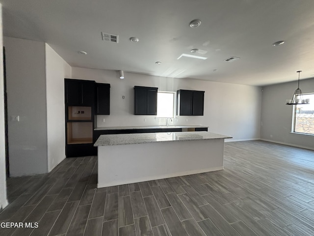 321 Merced Ct, El Paso, TX 79932 - kitchen with a sink, dark cabinetry, a kitchen island, and dark wood finished floors