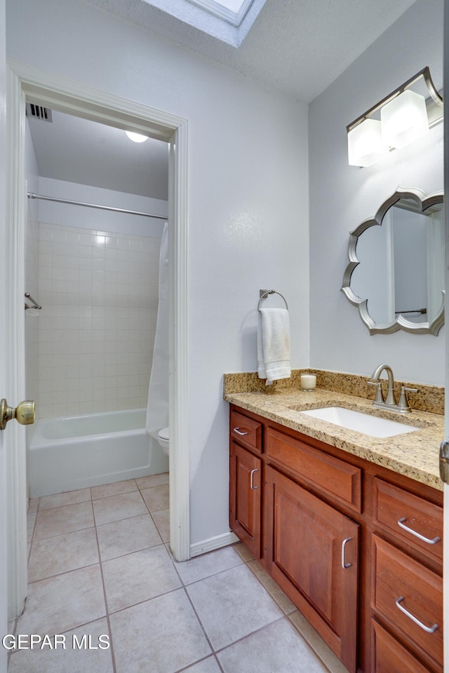 98 Northwind Dr, El Paso, TX 79912 - full bath featuring tile patterned flooring, vanity, shower / bathtub combination with curtain, toilet, and a skylight