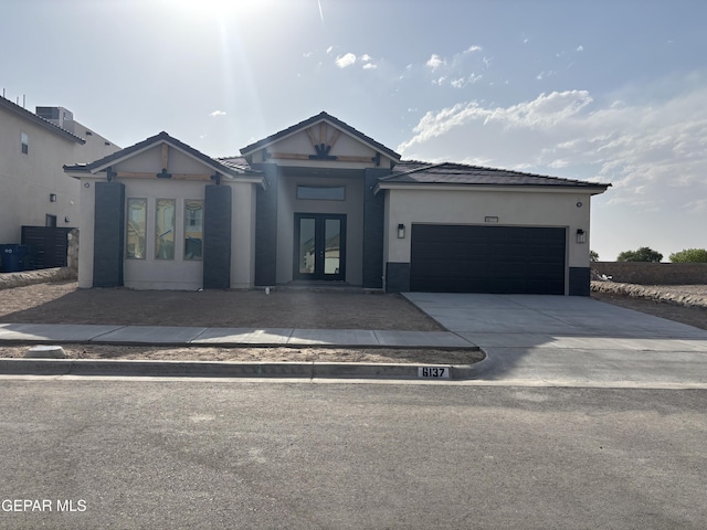 view of front facade featuring french doors, concrete driveway, a garage, and stucco siding