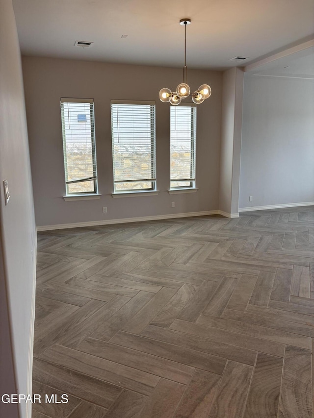 spare room with baseboards and a chandelier