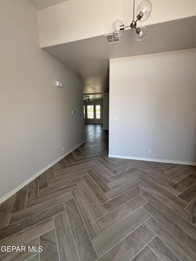 spare room featuring baseboards and a chandelier
