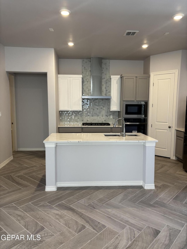 kitchen featuring wall chimney range hood, stainless steel appliances, a sink, baseboards, and tasteful backsplash