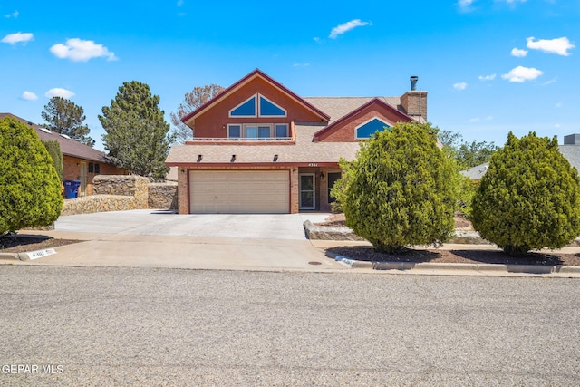 view of front of house with concrete driveway, brick siding, a chimney, and an attached garage
