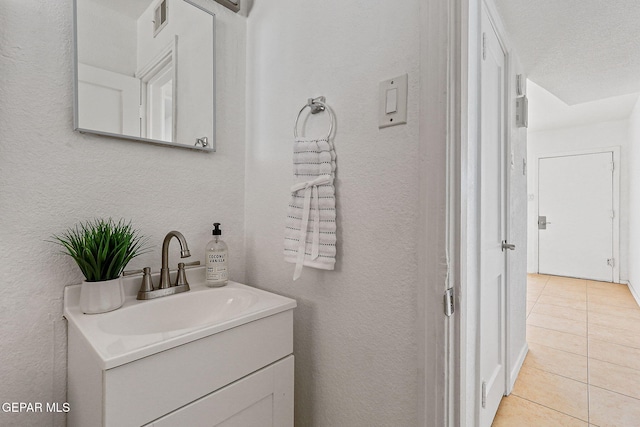 bathroom featuring tile patterned floors, vanity, and a textured wall