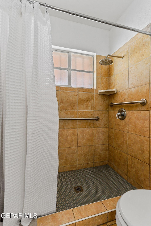 full bath featuring tiled shower and toilet