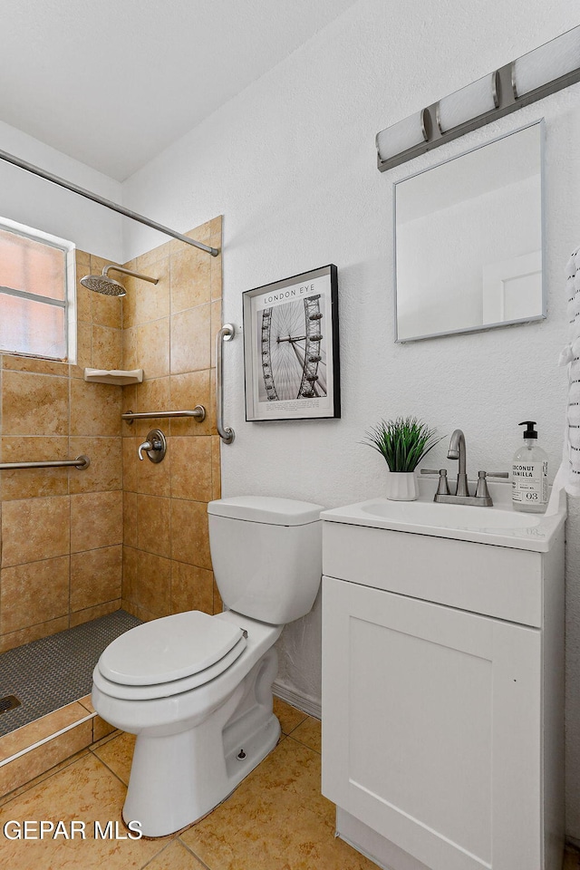 full bath with toilet, a tile shower, vanity, tile patterned flooring, and baseboards