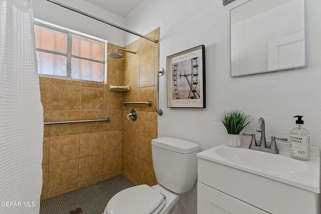 full bathroom with toilet, tiled shower, and vanity