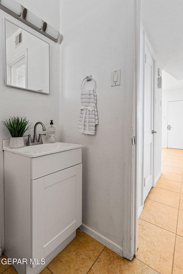 bathroom with tile patterned floors, baseboards, and vanity