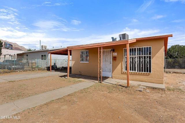 back of property with stucco siding, fence, cooling unit, and a carport