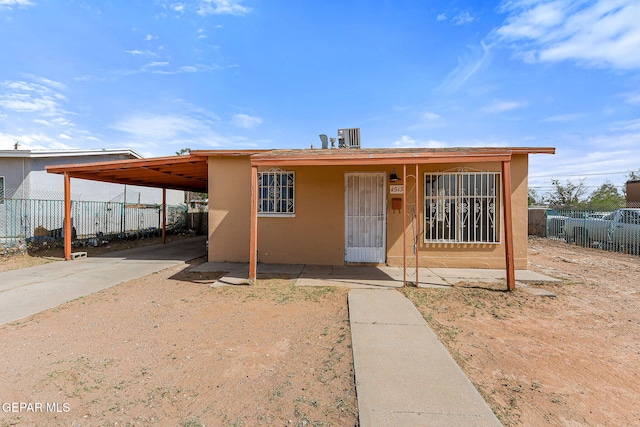 view of front of house with fence, concrete driveway, an attached carport, and stucco siding