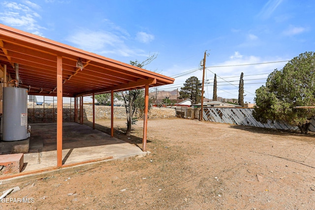 view of yard featuring gas water heater, fence, and a patio