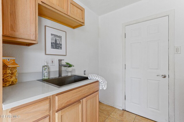 kitchen featuring a sink, light countertops, light tile patterned floors, and light brown cabinets