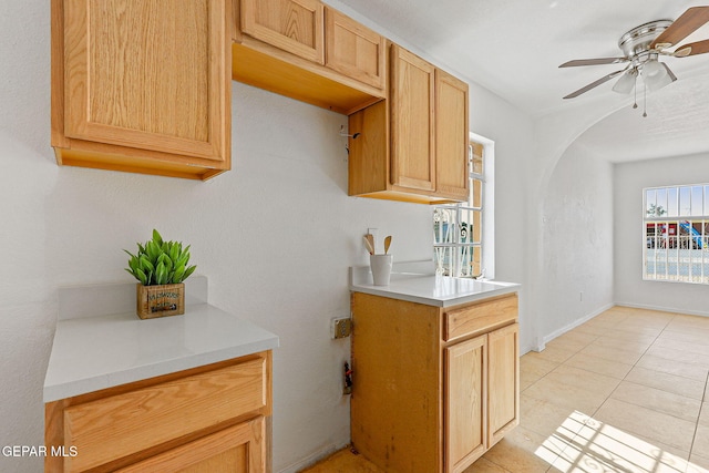 kitchen with light countertops, ceiling fan, light tile patterned floors, and arched walkways