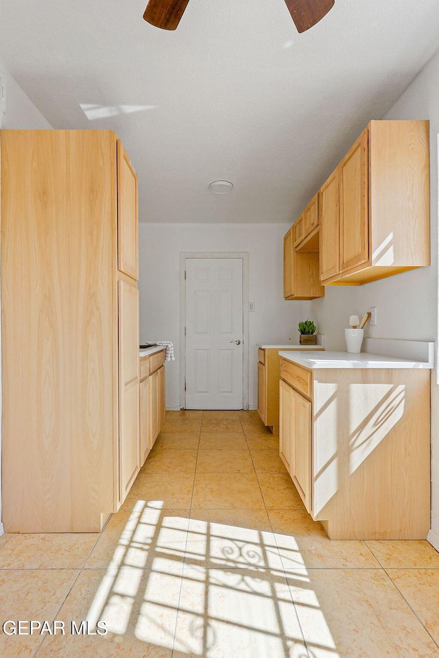 kitchen with light countertops, light tile patterned flooring, a ceiling fan, and light brown cabinetry