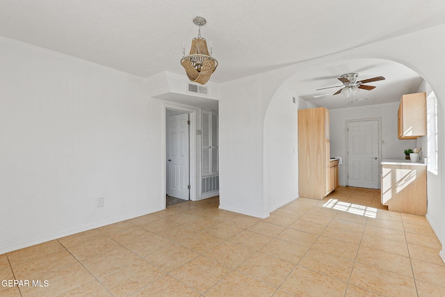 spare room featuring arched walkways, a chandelier, a ceiling fan, and light tile patterned floors